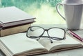 Eyeglasses on open notebook with book,pen and coffee cup Royalty Free Stock Photo