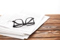 eyeglasses on pile of newspapers on wooden table, on white Royalty Free Stock Photo