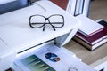 Eyeglasses on printer with books