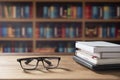 Eyeglasses and stacked books with laptop on wooden desk in home office room Royalty Free Stock Photo