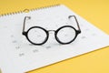 Eyeglasses on white clean calendar on yellow background using as thinking about plan, schedule or meeting apointment concept