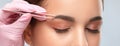 Eyelash artist plucks eyebrows with tweezers. Beautiful girl having Permanent Make-up Tattoo on her Eyebrows. Professional makeup Royalty Free Stock Photo