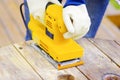 Eyellow electric sander over a wood table