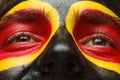 Eyes of German or Belgian sports fan patriot. Painted country flag on man face Royalty Free Stock Photo