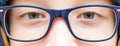 Eyes of an intelligent teenage boy wearing blue fashionable stylish glasses close up, outdoors Royalty Free Stock Photo