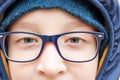 Eyes of an intelligent teenage boy wearing blue fashionable stylish glasses close up, outdoors Royalty Free Stock Photo