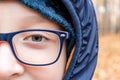 Eyes of an intelligent teenage boy wearing blue fashionable stylish glasses close up, outdoors Royalty Free Stock Photo