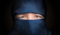 Eyes of young woman veiled with blue niqab scarf. Low key photo