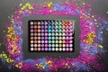 Eyeshadow palette with colorful eyeshadows crumbled on black background. Flat lay