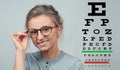 Eyesight check. Woman in glasses on the background of eye test chart Royalty Free Stock Photo