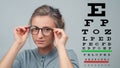 Eyesight check. Woman in glasses on the background of eye test chart Royalty Free Stock Photo