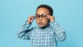 Eyesight. Portrait of little black boy wearing eyeglasses looking at camera, standing on blue studio background Royalty Free Stock Photo