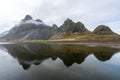 Eystrahorn mountain peaks with fog around and beautiful reflections in the calm lake. Royalty Free Stock Photo
