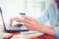 F young businessman working on his laptop and using credit card sitting at wooden table Royalty Free Stock Photo