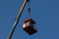 Faak Am See, Austria - August 09, 2025: Crane lifting a red construction platform with workers against a clear blue sky, Royalty Free Stock Photo