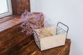 A fabric box with dry purple flowers on wooden planks against a white wall. interior element Royalty Free Stock Photo