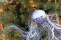 Fabric Christmas ball with many threads hangs on a Christmas tree with a garland