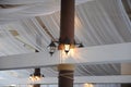 Fabric drape on the restaurant ceiling. Bright interior, lighted lantern. The decor for the wedding party