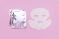 Fabric face mask, clean shiny packaging on pink background. Concept of natural cosmetics, face care, spa, face cream, women`s