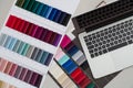 Fabric swatches and laptop for design project, material samples with color palette and computer, textile selection for Royalty Free Stock Photo
