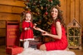 Fabulous Christmas holidays mom and daughter in red dresses decorate the Christmas tree. Cozy family holiday Royalty Free Stock Photo