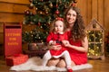 Fabulous Christmas holidays mom and daughter in red dresses decorate the Christmas tree. Cozy family holiday Royalty Free Stock Photo