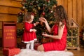 Fabulous Christmas holidays mom and daughter in red dresses decorate the Christmas tree. Cozy family holiday Royalty Free Stock Photo