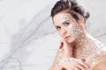 Fabulous fashion portrait of a young beautiful woman with transparent crystals on her face and shoulders.