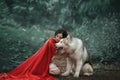 Fabulous image, dark-haired brunette attractive lady in short white dress, long red scarlet cloak lying on ground sits Royalty Free Stock Photo