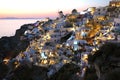 Fabulous picturesque village of Oia built on the rocks with traditional white houses and windmills in Santorini island at sunset Royalty Free Stock Photo