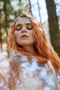 Fabulous portrait of a red-haired girl in nature with double exposure and glare. Beautiful redhead girl with long hair in forest Royalty Free Stock Photo