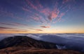Fabulous sunset high in the mountains above the clouds. Aerial view of dramatic mountain landscape at dusk with fog and soft light Royalty Free Stock Photo