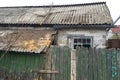 Facade of abandoned rickety brick house in village  behind green wooden fence. Close-up Royalty Free Stock Photo