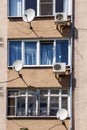 The facade of an apartment building with air conditioning and satellite television antennas Royalty Free Stock Photo