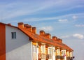 Facade of apartment building with terracotta tile roof shingles against blue sky Royalty Free Stock Photo