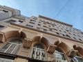 A facade with arched windows and decorative geometric structures on a tall beige building. The photo emphasizes