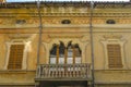 Facade of the baroque yellow building with windows and shutters, balcony with plants in the cente Royalty Free Stock Photo