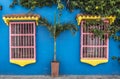 Facade of a blue colonial house with colorful windows in the old center of Cartagena in Colombia