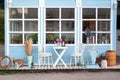 Facade blue Cozy home with a beautiful garden in summer. Beautiful farmhouse with wicker baskets and green plants on terrace. Whit Royalty Free Stock Photo