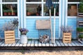 Facade blue home with garden tools: shovel, pitchfork, rake, firewood and pots flowers. Cozy Autumn decor veranda house. Gardening Royalty Free Stock Photo