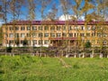 The facade of the boarding school is hidden behind poplar trees on a sunny summer day in the village of Parnaya. Krasnoyarsk