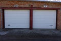 Facade of a brown brick garage with two gray gates in the street