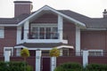 Facade of a brown brick private house with an iron balcony and windows behind a concrete fence Royalty Free Stock Photo