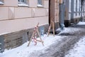 The facade of the building is fenced off with warning tape from falling icicles on the snow-covered and poorly cleared sidewalk Royalty Free Stock Photo