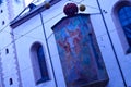 The facade of the church with a fresco depicting Jesus. Two arched windows. Wall mounted lively biblical motifs depicting a savior