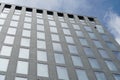 A facade of a corporate building, the windows reflecting sky. Only one of all the windows is open which distorts the uniformity un Royalty Free Stock Photo