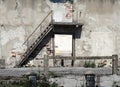 Facade, entrance and staircase of an abandoned and ruined two story house.