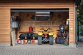 Facade front view open door ATV quad bike motorcycle parking messy garage building with wooden siding at home driveway backyard Royalty Free Stock Photo