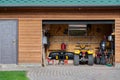 Facade front view open door ATV quad bike motorcycle parking messy garage building with wooden siding at home driveway backyard Royalty Free Stock Photo