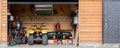 Facade front view open door ATV quad bike motorcycle parking messy garage building with wooden siding at home driveway Royalty Free Stock Photo